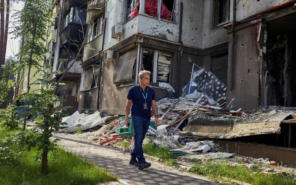 Hollywood actor and Goodwill Ambassador Ben Stiller walks past a damaged building as he visits the Lypki neighbourhood in Irpin, Ukraine - UNHCR/Andrew McConnell