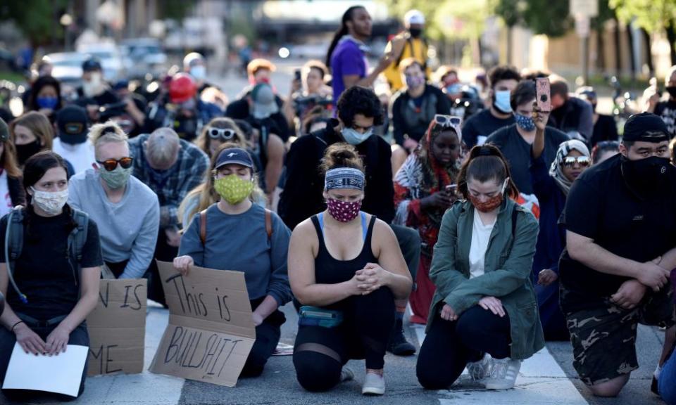 Kneeling protesters in face masks observe a moment of silence in Minneapolis