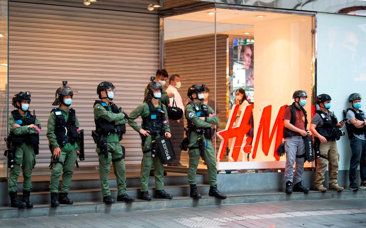 Police officers stand guard in front of a closed clothing store in Causeway Bay during a protest on China's National Day, - Jayne Russell/AFP