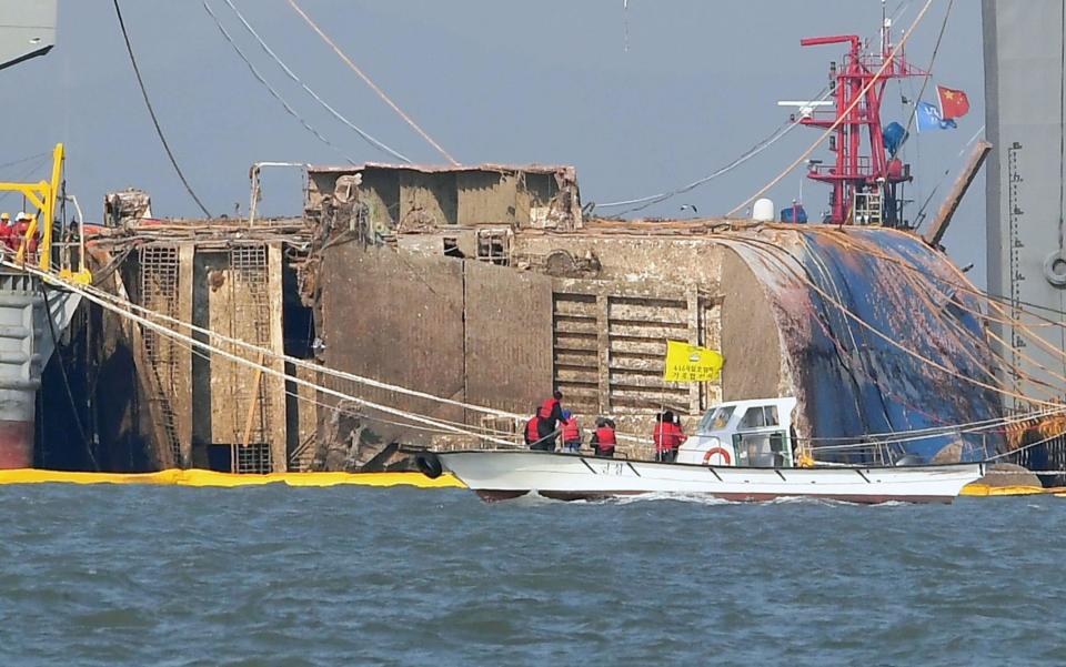 Relatives of missing passengers of the sunken Sewol ferry on a boat, front, watch its salvage operation in waters off Jindo, South Korea - Credit: Kyodo News 