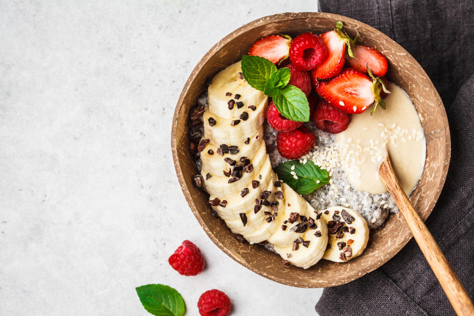 Chia pudding with berries, banana, peanut butter and cocoa nibs in a coconut shell bowl.