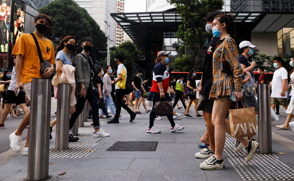People cross a street at the shopping district of Orchard Road as the city state reopens the economy, amid the coronavirus disease (COVID-19) outbreak, in Singapore June 19, 2020.  REUTERS/Edgar Su