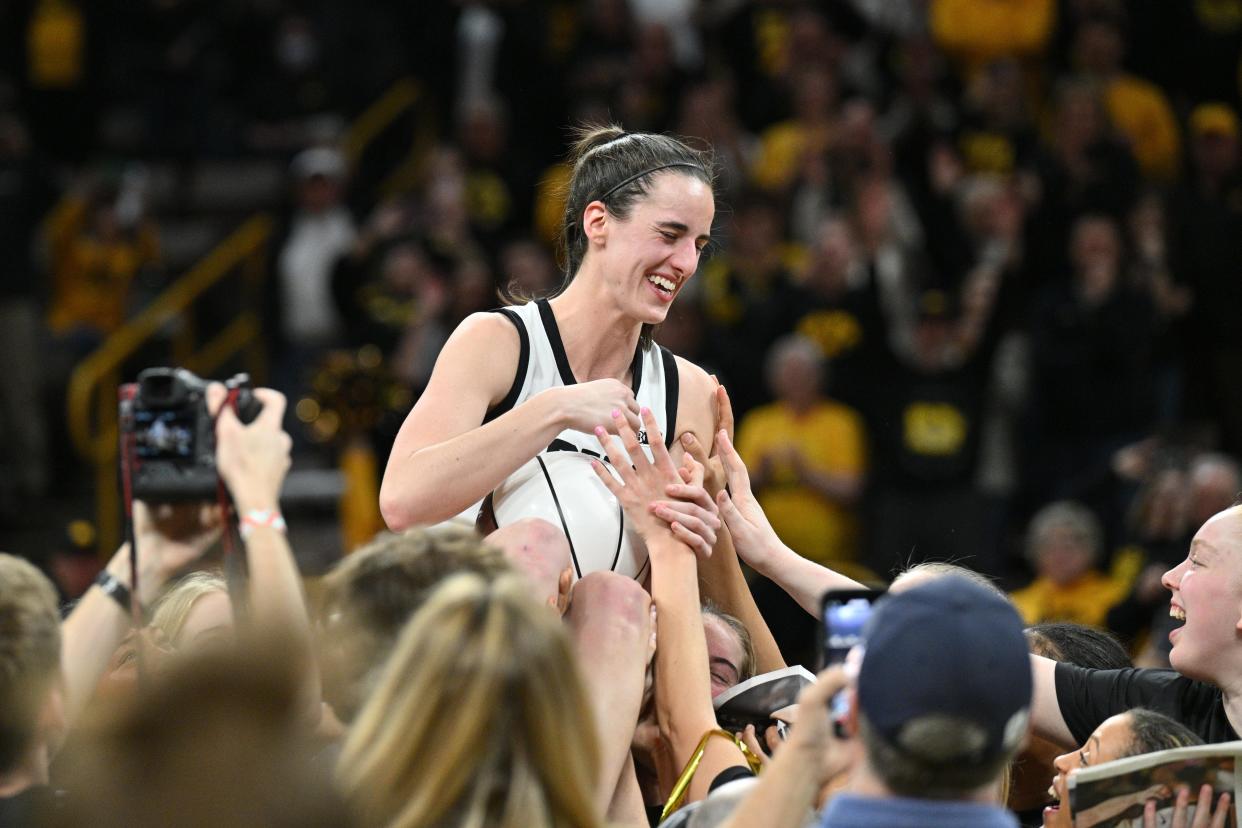 Iowa players lift up teammate Caitlin Clark in a postgame celebration of her new NCAA women's scoring record.