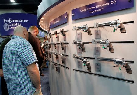 Gun enthusiasts look over guns at the National Rifle Association's (NRA) annual meetings and exhibits show in Louisville, Kentucky, May 21, 2016. REUTERS/John Sommers II/File Photo