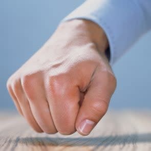 close up of fist knocking on wood table