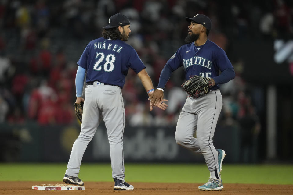 Seattle Mariners third baseman Eugenio Suarez (28) and left fielder Dylan Moore (25) celebrate after a 9-7 win over the Los Angeles Angels in a baseball game in Anaheim, Calif., Friday, Aug. 4, 2023. (AP Photo/Ashley Landis)