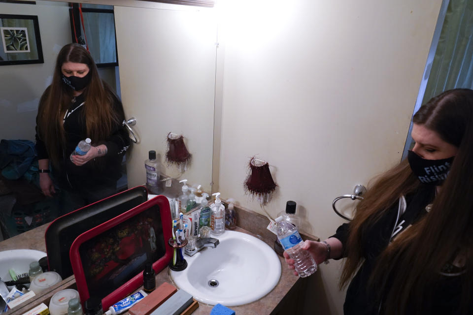 Melissa Mays grabs a bottle of water in the bathroom of her home in Flint, Mich., Wednesday, Jan. 13, 2021. Some Flint residents impacted by months of lead-tainted water are looking past expected charges against former Gov. Rick Snyder and others in his administration to healing physical and emotional damages left by the crisis. (AP Photo/Paul Sancya)