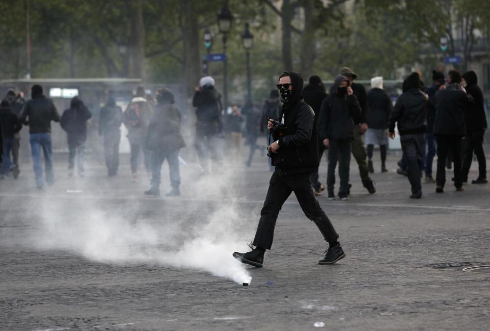 Trouble: Youths walk near tear gas grenades as they scuffle with riot police officers during a protest against Ms Le Pen in Paris (AP)