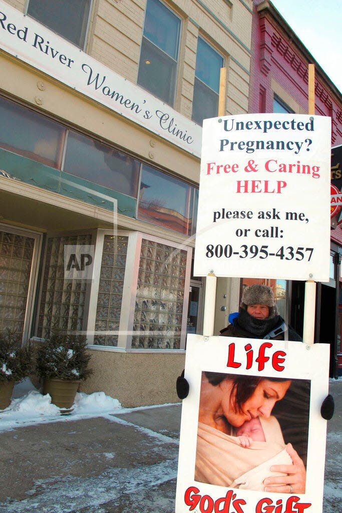 FILE - An abortion protester stands outside the Red River Valley Women's Clinic in Fargo, N.D., on Feb. 20, 2013. North Dakota's only abortion clinic, the Red River Women's Clinic, has gone to federal court seeking to declare the state's imminent abortion ban is contrary to the state constitution. (AP Photo/Dave Kolpack, File)