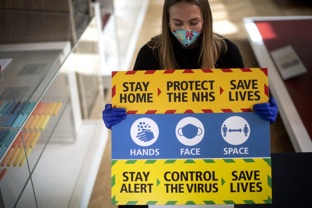 A staff member holds three signs from the Downing Street briefings (PA) (PA Archive)