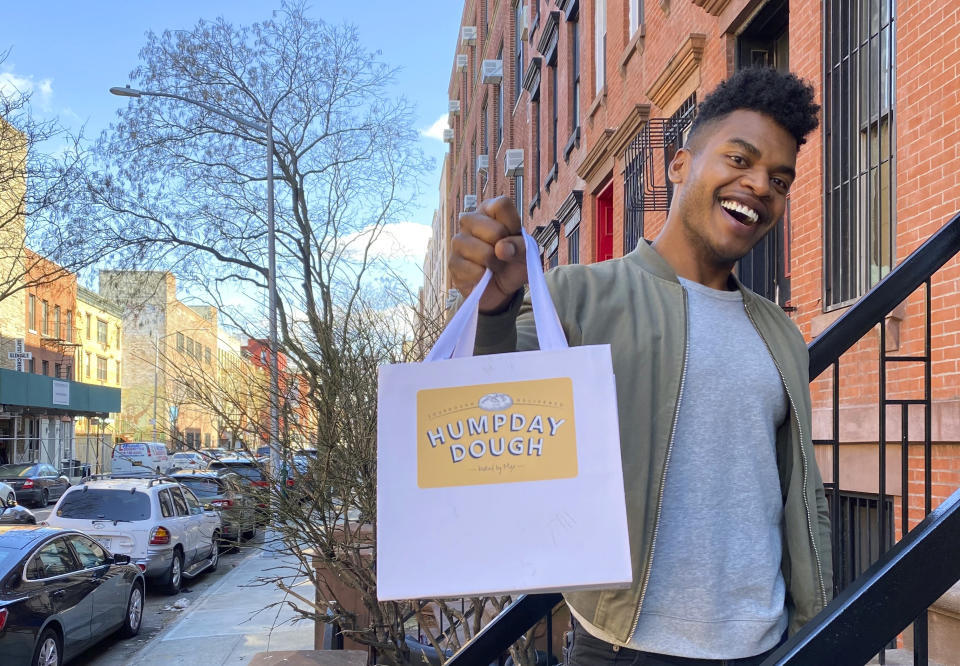 Broadway performer Max Kumangai holds a bag promoting his company Humpday Dough in New York. The triple threat from the musical “Jagged Little Pill” has leaned into a fourth skill as the pandemic marches on: baking and selling his own sourdough. (Michael Lowney/Humpday Dough via AP)