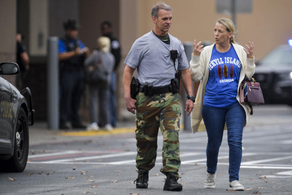 A police officer speaks to a woman outside a Walmart store, Wednesday, Dec. 7, 2022, in Kennesaw, Ga. Police in suburban Atlanta say one person was shot and injured in a shooting near the automotive center at a Walmart store. Investigators said two groups of people had a dispute outside the store in Cobb County and shots were fired. (AP Photo/Mike Stewart)