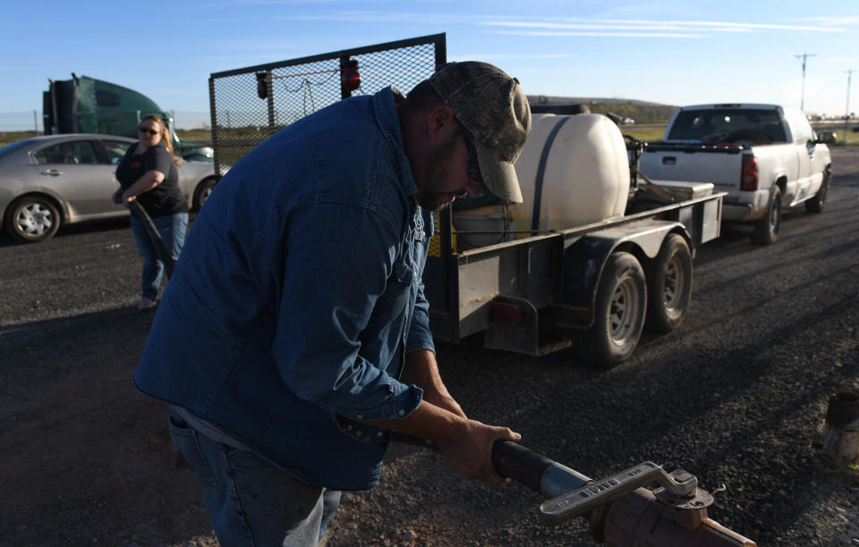 Ray Smith and his wife, Tara, hook up a hose at a water distributing station to fill their pressure-washer tank. (Photo: Mark Sterkel/Odessa American)