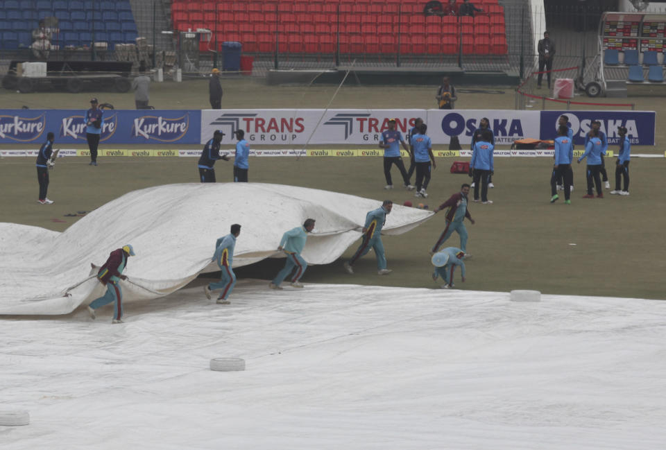 Ground staff cover a pitch during a light rain at Gaddafi stadium, in Lahore, Pakistan, Monday, Jan. 27, 2020. Pakistan and Bangladesh are scheduled to play the last T20 which is delayed due to rain in Lahore. (AP Photo/K.M. Chaudary)