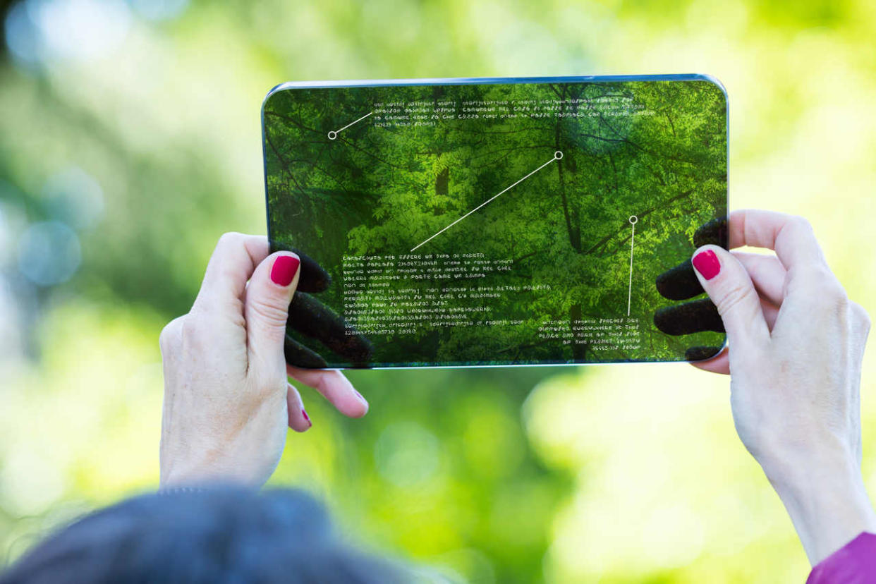  Hands of a woman using augmented reality on a high tech transparent digital tablet. 