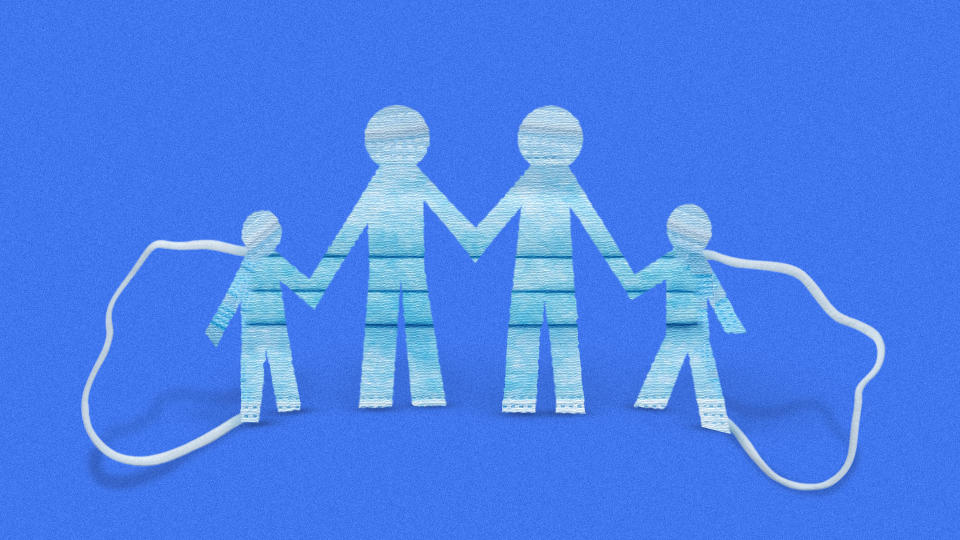 The blue side of a surgical mask cut into a pattern showing two adults and two children.