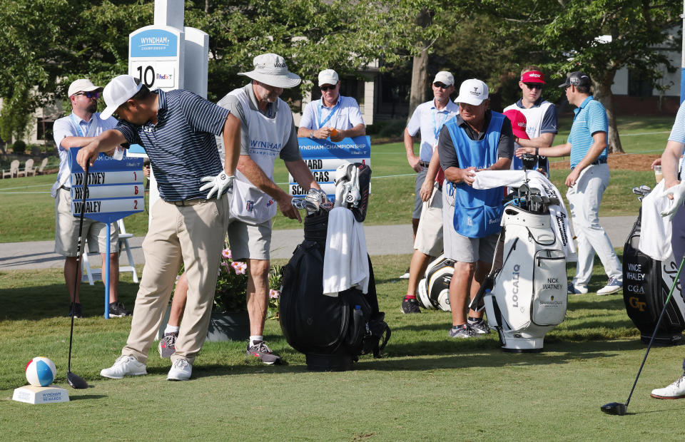 John Huh, left, wipes his forehead as he waits for a lengthy delay while three groups tie up the tenth tee during the first round of the Wyndham Championship golf tournament , Thursday, Aug. 4, 2022, in Greensboro, NC. (AP Photo/Reinhold Matay)