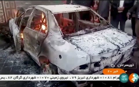 People stand near a burning car in Zanjan, Iran, in this still image taken from video on January 1, 2018 - Credit: REUTERS