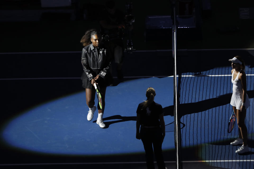 Serena Williams, left, of the United States, walks onto the court for the opening coin toss for her match against Magda Linette, right, of Poland, during the first round of the U.S. Open tennis tournament, Monday, Aug. 27, 2018, in New York. (AP Photo/Jason DeCrow)