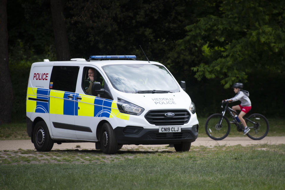 CARDIFF, UNITED KINGDOM - MAY 16: A police officer looks out from a police van in Bute Park during the coronavirus lockdown period as a cyclist passes behind on May 16, 2020 in Cardiff, United Kingdom. The prime minister announced the general contours of a phased exit from the current lockdown, adopted nearly two months ago in an effort curb the spread of Covid-19. (Photo by Matthew Horwood/Getty Images)