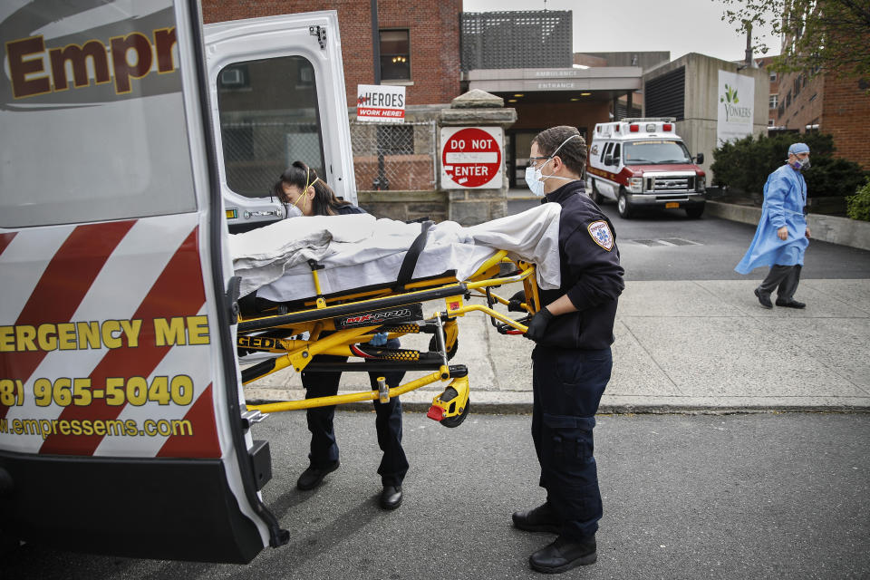 Emergency medical technicians load a patient into an ambulance as Dr. Anthony Leno, Director of Emergency Medicine, stands outside at the end of his shift, Monday, April 20, 2020, at St. Joseph's Hospital in Yonkers, N.Y. (AP Photo/John Minchillo)