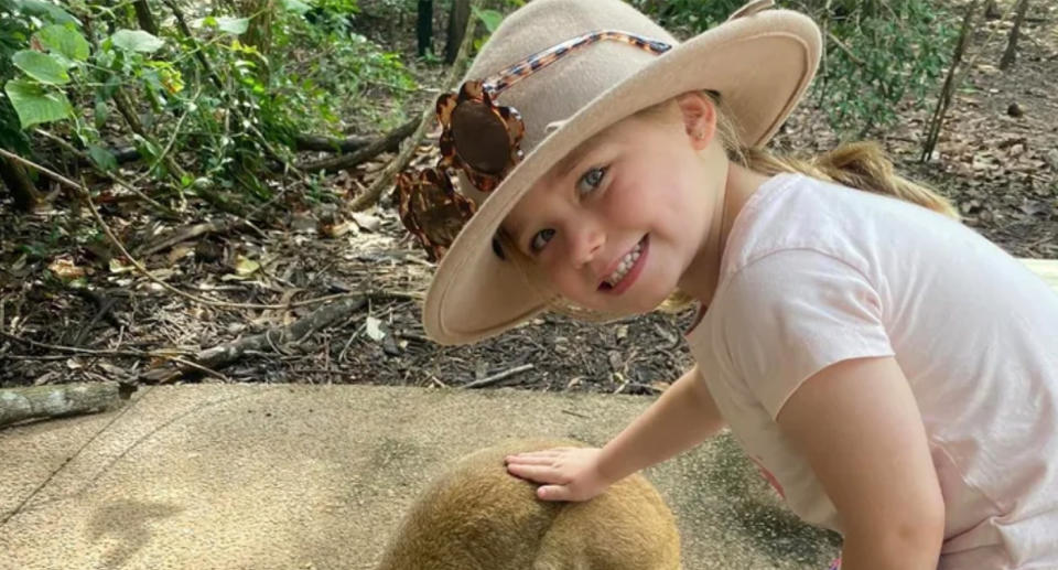 Millicent Edwards wearing a hat and patting a wallaby. 