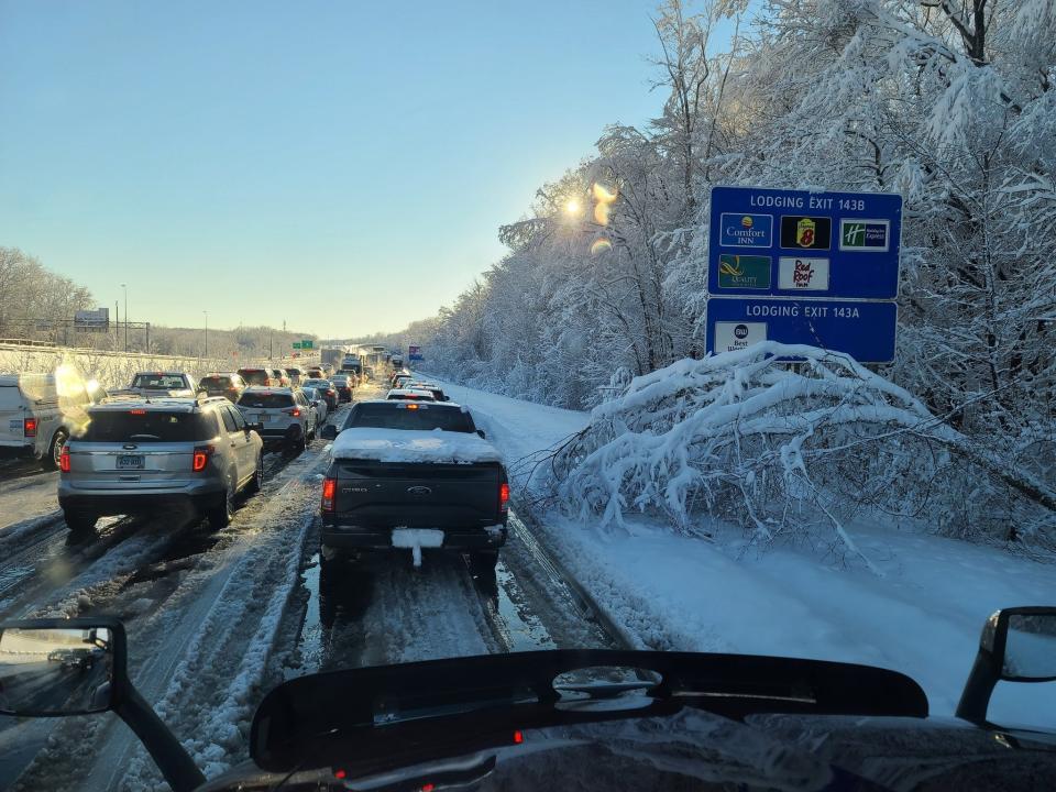 A view of snow-covered trucks and cars stuck in traffic on the I-95 during the day.