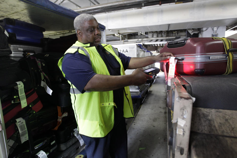 In this Wednesday, Aug. 1 2012 photo, an American Airlines fleet clerk uses a Ramp-Link to scan luggage at JFK International airport in New York. Travelers still have to put up with packed planes, rising fees and unpredictable security lines, but they are missing fewer business meetings or chances to tuck their kids into bed. Nearly 84 percent of domestic flights arrived within 15 minutes of their schedule time in the first half of the year, the best performance since the government started tracking such data in 1988. (AP Photo/Mary Altaffer)