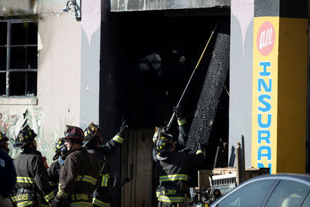 Firefighters remove debris at a warehouse after a fire broke out during an electronic dance party late Friday evening, resulting in at least nine deaths and many unaccounted for in the Fruitvale district of Oakland, California, U.S. December 3, 2016. REUTERS/Stephen Lam