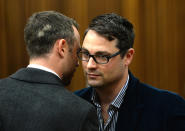 Oscar Pistorius, talks with his brother Carl, right, inside court on the second day of his trial at the high court in Pretoria, South Africa, Tuesday, March 4, 2014. Pistorius is charged with murder for the shooting death of his girlfriend, Reeva Steenkamp, on Valentines Day in 2013. (AP Photo/Antoine de Ras, Pool)