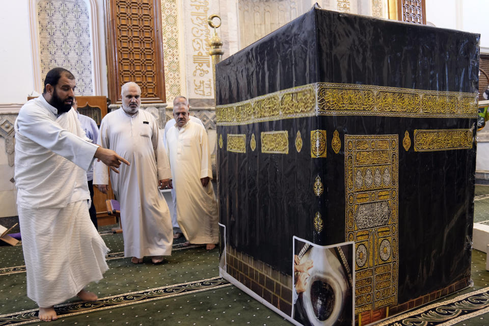 Iraqi pilgrims walk around the model of Kaaba during a lecture on performing the Hajj rituals in Tikrit, Iraq, Saturday, May 20, 2023. (AP Photo/ Hadi Mizban)