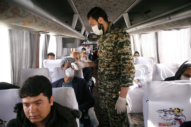 A member of the Islamic Revolution Guards Corps (IRGC) troops measures a temperature, following the outbreak of coronavirus disease (COVID-19) in the bus at the entrance of Qom
