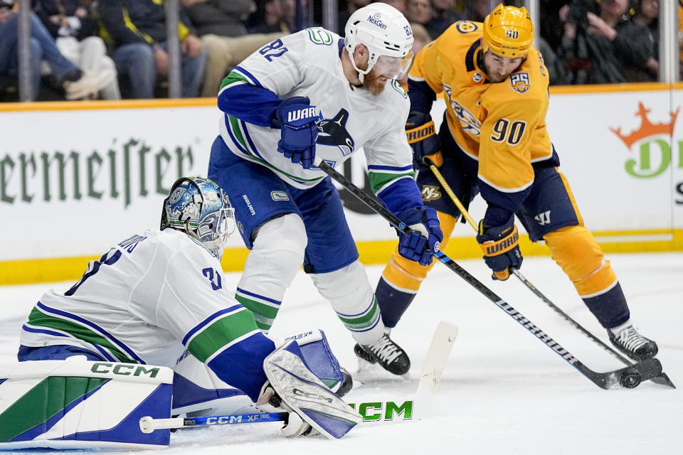 Vancouver Canucks defenseman Ian Cole (82) passes the puck away from Nashville Predators center Ryan O'Reilly (90) during the second period in Game 6 of an NHL hockey Stanley Cup first-round playoff series Friday, May 3, 2024, in Nashville, Tenn. (AP Photo/George Walker IV)