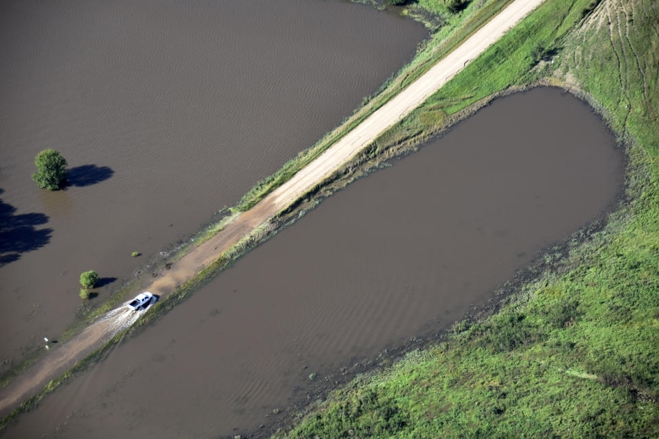 This Saturday, Sept. 14, 2019, aerial photo provided by the South Dakota Civil Air Patrol shows a pickup truck traveling on a partially flooded road in South Dakota's Rosedale Township. (South Dakota Civil Air Patrol via AP)