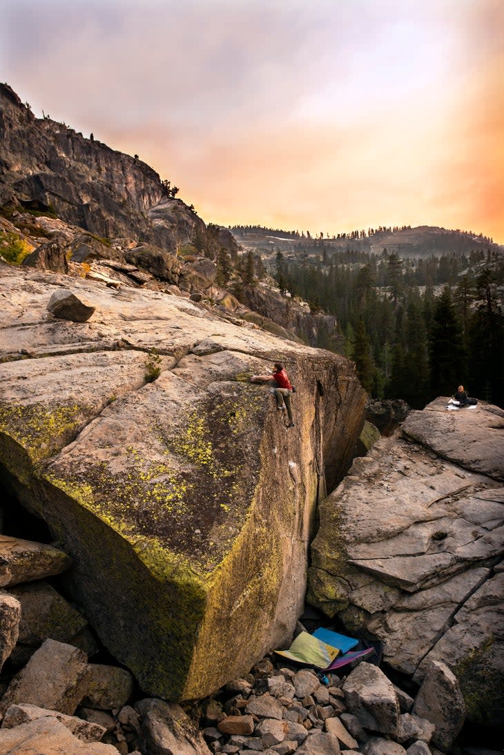 A zoomed out shot of Jimmy Webb climbing an enormous boulder near Lake Tahoe