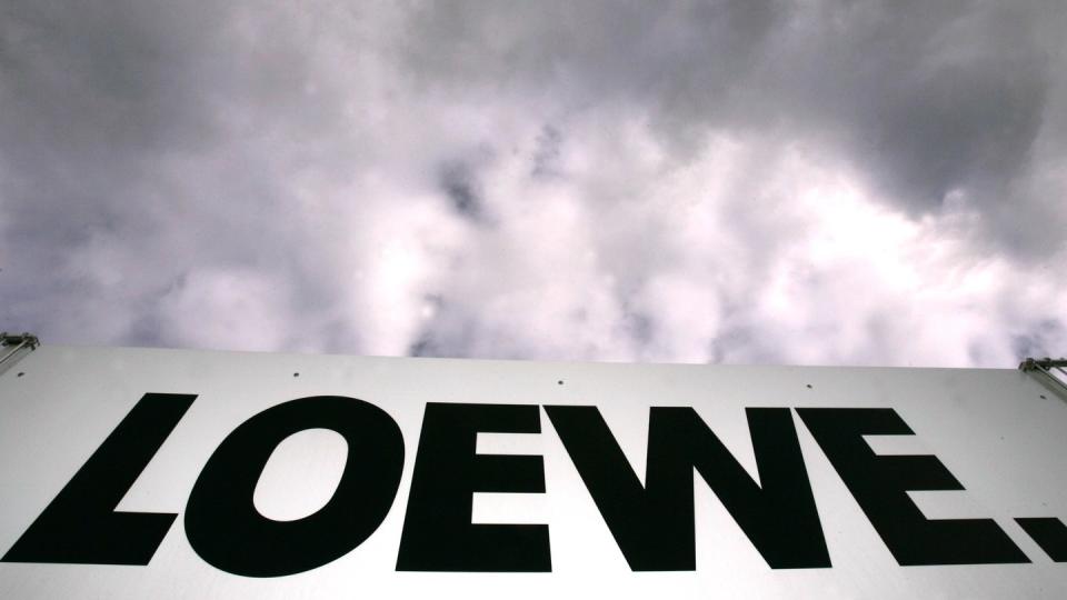 Das Loewe-Firmenlogo hängt vor dem bewölkten Himmel am Zaun des Betriebsgeländes in Kronach. Foto: Marcus Führer