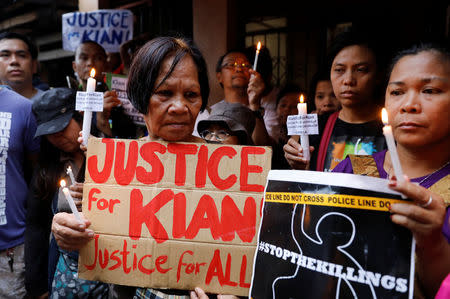 Protesters hold placards and lit candles at the wake of Kian Loyd delos Santos, a 17-year-old high school student, who was among the people shot dead last week in an escalation of President Rodrigo Duterte's war on drugs, in Caloocan city, Metro Manila, Philippines August 21, 2017. REUTERS/Erik De Castro