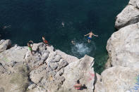 A youth jumps in the sea from a rock at Varkiza village, a few miles southwest of Athens, on Thursday, July 29, 2021. One of the most severe heat waves recorded since 1980s scorched southeast Europe on Thursday, sending residents flocking to the coast, public fountains and air-conditioned locations to find some relief, with temperatures rose above 40 C (104 F) in parts of Greece and across much of the region. (AP Photo/Yorgos Karahalis)