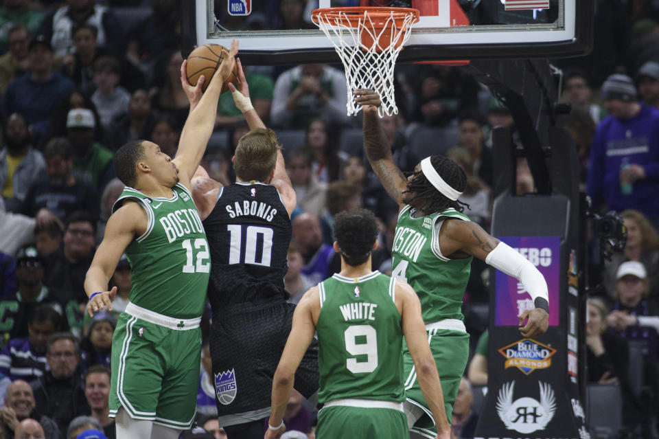 Sacramento Kings forward Domantas Sabonis (10) is guarded by Boston Celtics forward Grant Williams (12), guard Derrick White (9) and center Robert Williams III during the first quarter of an NBA basketball game in Sacramento, Calif., Tuesday, March 21, 2023. (AP Photo/Randall Benton)