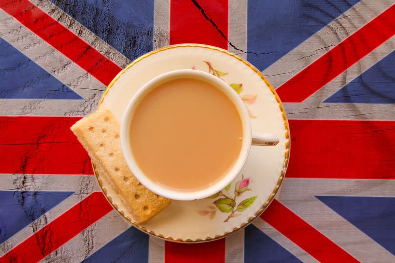 The Union Jack flag with a cup of tea served with a shortbread biscuit in a bone china cup and saucer