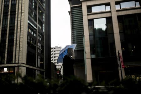 A businessman is seen through a window as he walks in a banking district on a rainy day in Tokyo, Japan, February 15, 2016. REUTERS/Thomas Peter