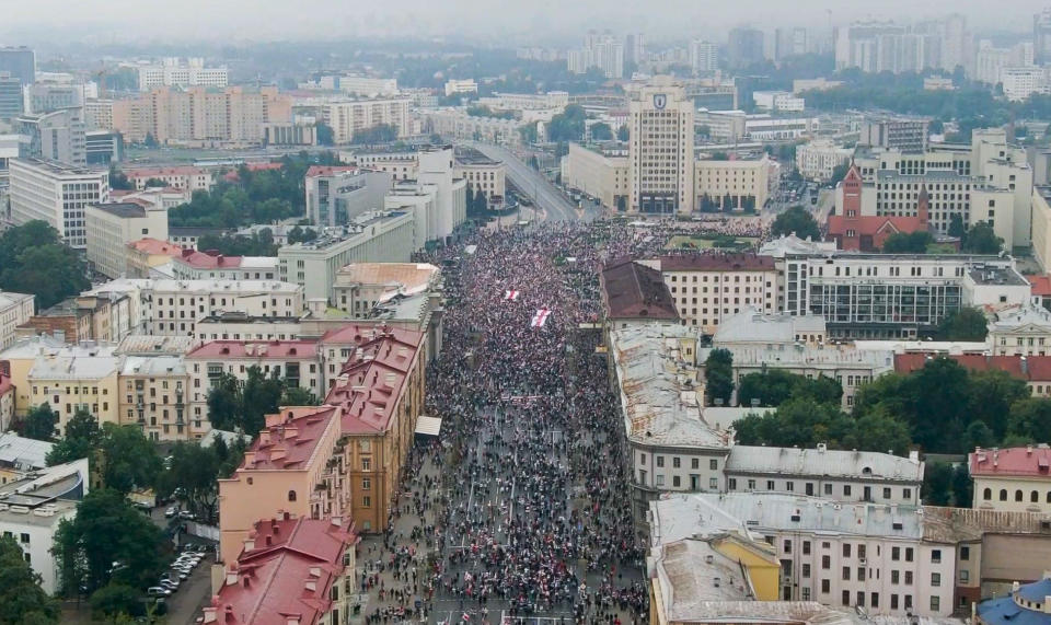 In this video grab taken from The Associated Press footage, Belarusian opposition supporters rally with old Belarusian national flags rally toward Independence Square in Minsk, Belarus, Sunday, Aug. 23, 2020. A vast demonstration with many thousands of protesters demanding the resignation of Belarus' authoritarian president are rallying in the capital, continuing the public dissent since the disputed presidential election.(AP Photo)