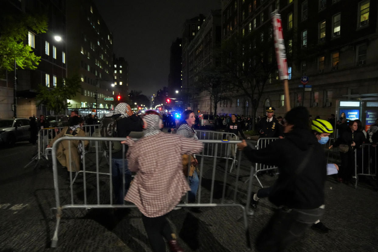 Protesters move barricades as police maintain a cordon around Columbia University.