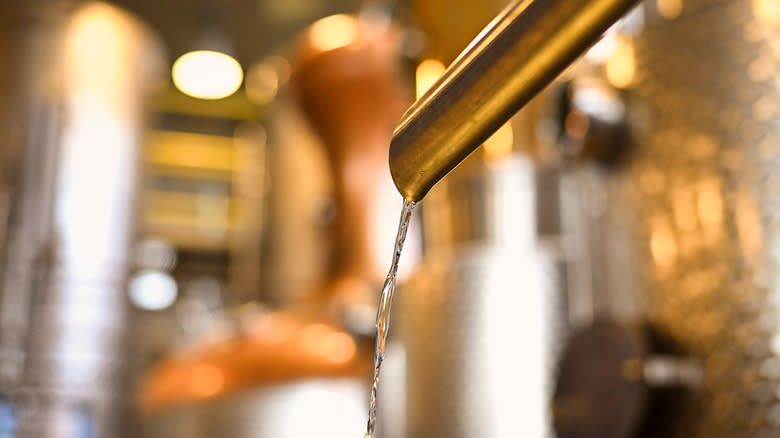 close up of whiskey still pouring distilled liquor