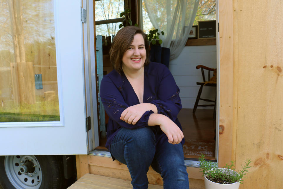 This photo provided by NerdWallet shows Annie Colpitts posing in a doorway of her tiny home, in Ashland, Va. Colpitts designed and helped build the home. (Courtesy of Annie Colpitts/NerdWallet via AP)