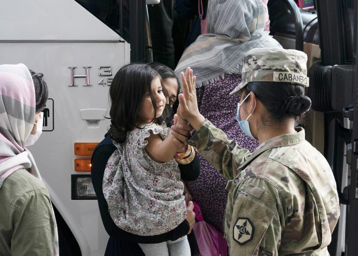 Army PFC Kimberly Hernandez, gives a high-five to a girl evacuated from Kabul, Afghanistan, before boarding a bus after they arrived at Washington Dulles International Airport in Chantilly, Va., on Aug. 30, 2021.