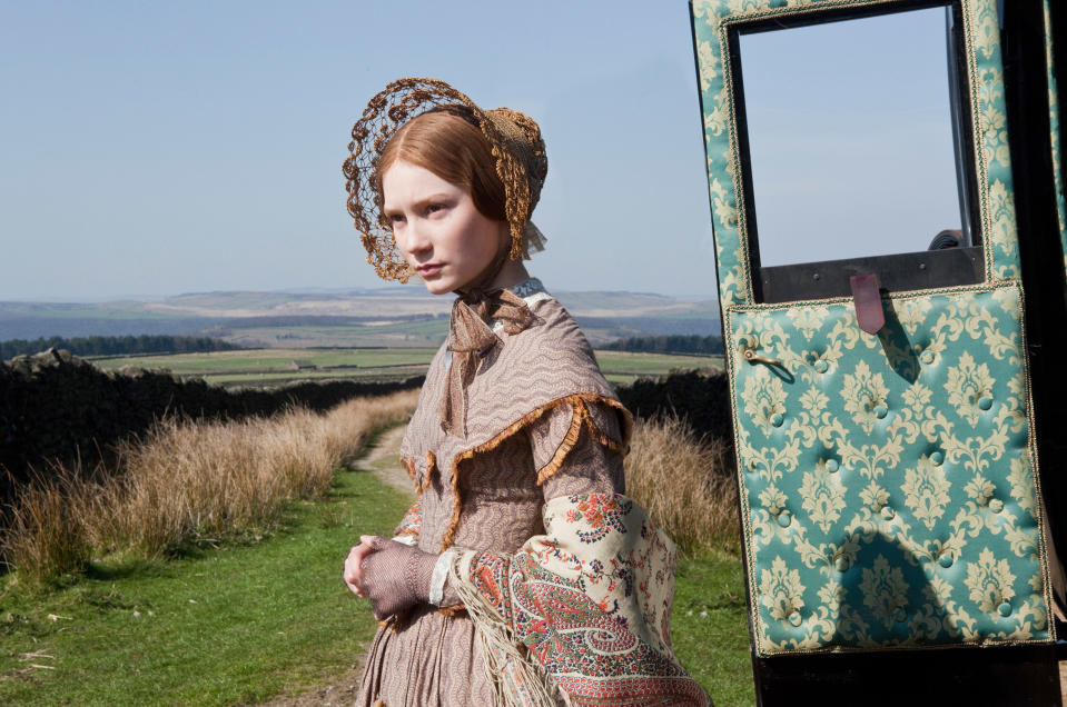 Mia Wasikowska stands outside a carriage