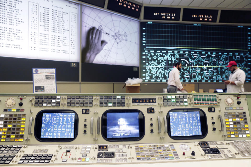 The console for Booster Systems Engineer, the first position on the first row known as "The Trench," has an overview of the Display and Projection screens as workers continue restoring the Apollo mission control room to replicate the Apollo mission era 50 years ago at the NASA Johnson Space Center Monday, June 17, 2019, in Houston. The screens are displaying, from left, spacecraft telemetry data, the position of astronauts in relation to Lunar Lander while on the moon and the position of the Command Module as it orbits the moon. (AP Photo/Michael Wyke)