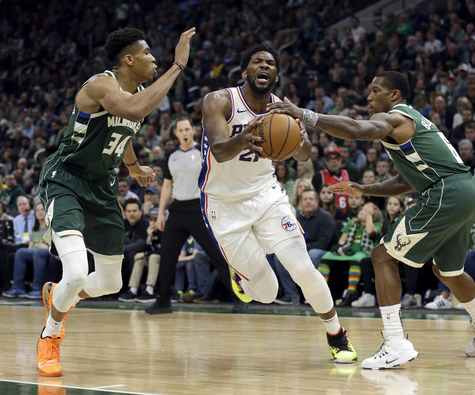 Philadelphia 76ers’ Joel Embiid drives between Milwaukee Bucks’ Giannis Antetokounmpo (34) and Eric Bledsoe (6) during the first half of an NBA basketball game Sunday, March 17, 2019, in Milwaukee. (AP Photo/Aaron Gash)