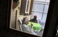 In this photo taken on Monday, June 22, 2020, Eric Baranyanka, right, speaks with his foster mother Emma Monsaert in Lembeek, Belgium. Baranyanka fled political persecution in the Belgian protectorate of Burundi in the 1960's, landing half a world away at a military airport in Brussels, before being fostered by Emma Monsaert and her husband Paul. (AP Photo/Virginia Mayo)